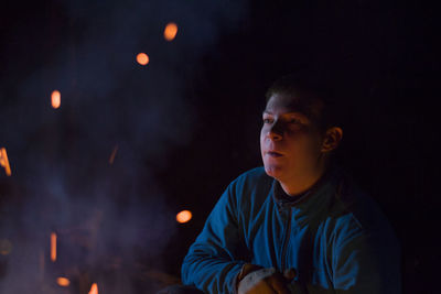 Young man by campfire at night