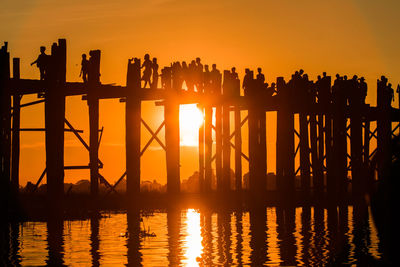 Silhouette people on pier against sky during sunset