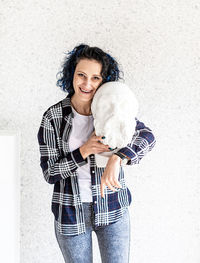 Portrait of smiling young woman standing against wall