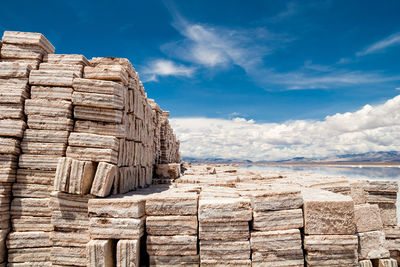 Rock formations on coast against cloudy sky