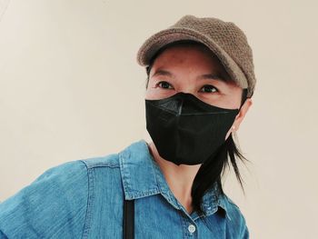 Woman wearing mask looking away against wall