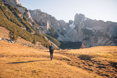 Rear view of man standing on mountain against sky