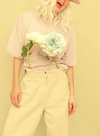 Midsection of laughing woman wearing cap with flowers standing against colored background