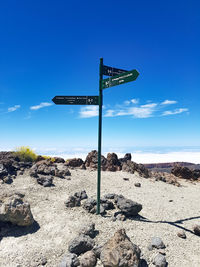 Sign board on rock against sky