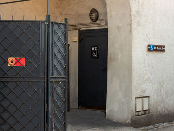 Public toilet door with wheelchair sign reserved for the disabled.  next to it an iron screen