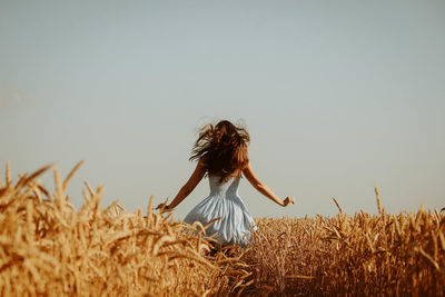 Rear view of woman on field against clear sky