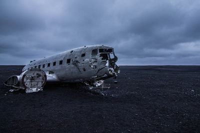 Abandoned airplane on beach against sky