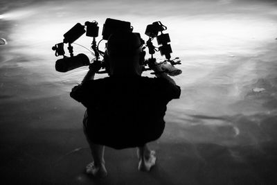 Rear view full length of man with lighting equipment in sea at night