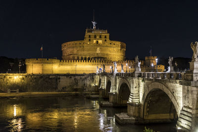 Arch bridge over river at night