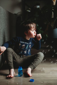 Rear view of boy sitting on floor at home