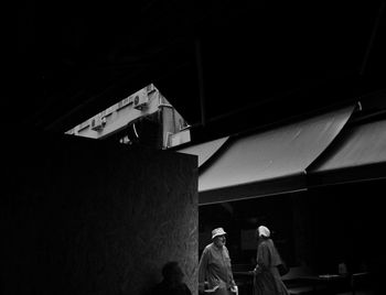 Rear view of people walking on building at night