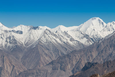 Scenic view of snowcapped mountains against blue sky