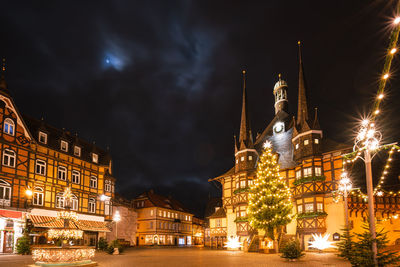 Illuminated buildings in city against sky at night