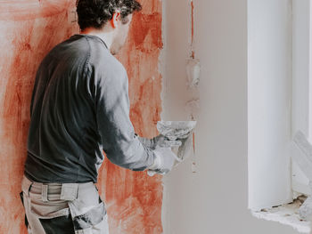 Side view of man standing against wall