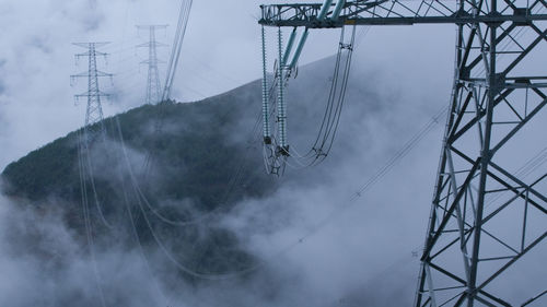 Low angle view of electricity pylon against sky