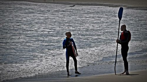 Rear view of friends standing on beach