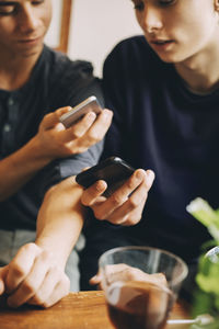 Midsection of man using mobile phone while sitting on table