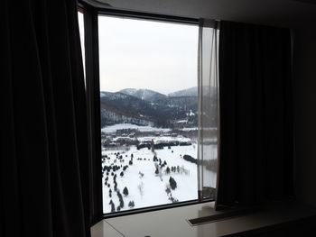View of snow covered landscape through window