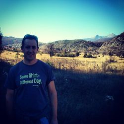 Portrait of smiling man standing on landscape against clear sky