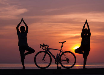 Low angle view of silhouette man by bicycle against sky during sunset