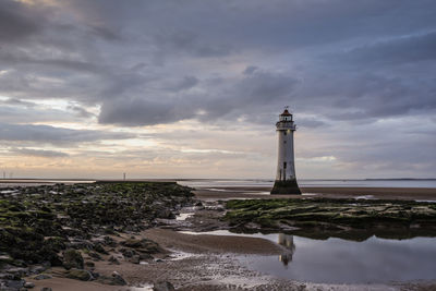 Lighthouse amidst sea and buildings against sky