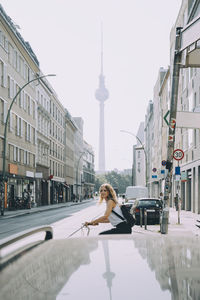 Side view of young woman riding bicycle on street in city