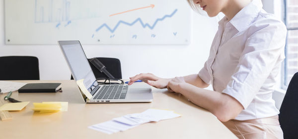 Businesswoman working in office with laptop at desk.