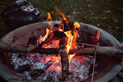 High angle view of sausages on burning woods in fire pit at campsite