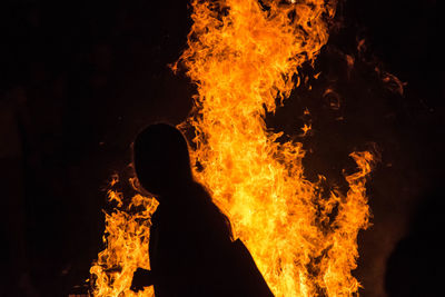 Side view of silhouette woman against fire at night