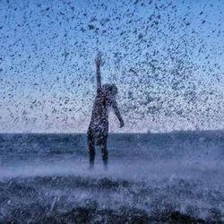 Full length of silhouette man splashing water in sea