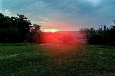 Scenic view of grassy field against sky at sunset