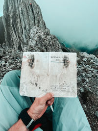 Midsection of man reading book on rock