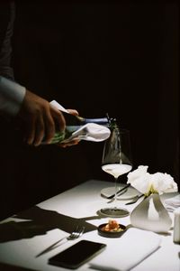 Cropped hand of woman holding wineglass on table