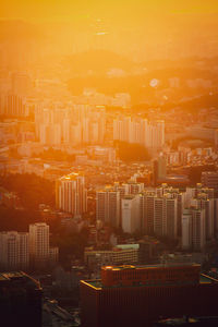 Aerial view of buildings in city against orange sky