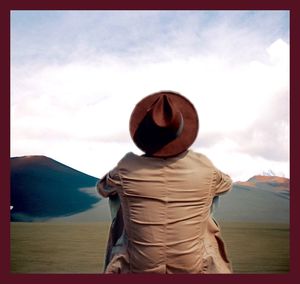 Rear view of man looking at mountains against sky