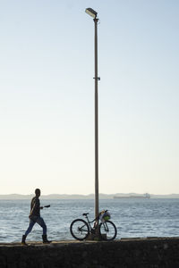 Bicycle on street by sea against clear sky