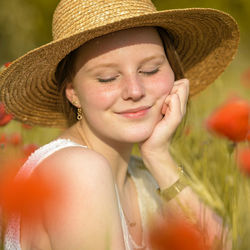 Smiling young woman wearing hat amidst field