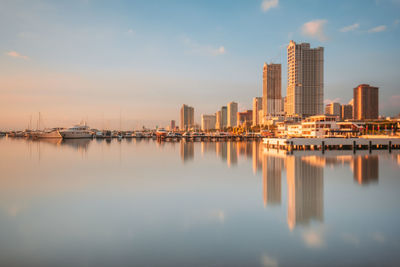 Sailboats in city by buildings against sky