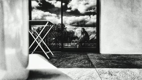 Boy sitting by tree against sky