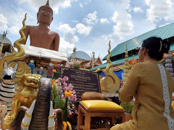 Rear view of woman praying against buddha statue