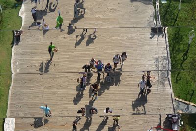 Reflection of people walking at footpath on mirror in park