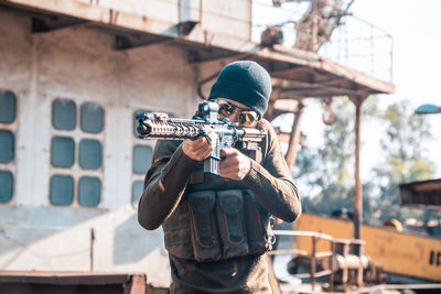 Man holding camera while standing against built structure