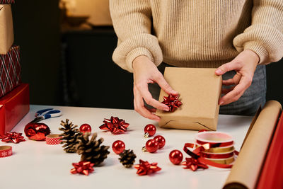 Woman packaging gift box in craft paper, present for christmas surprise