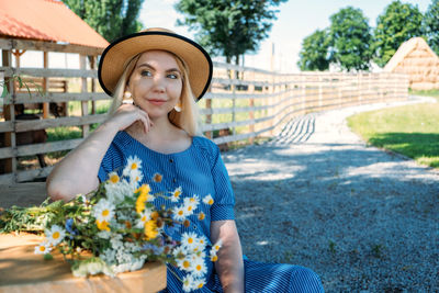 Portrait of young woman looking away while sitting by plants