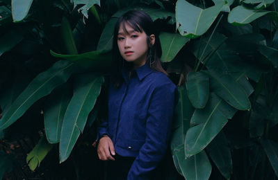 Portrait of serious girl standing by plants