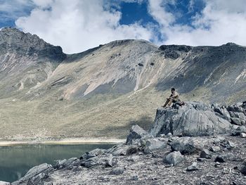 Man sitting by lake on rock