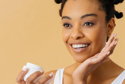 Portrait of young woman holding coffee against white background