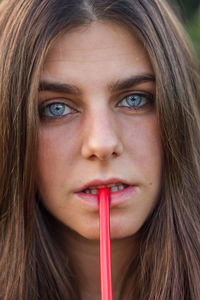 Close-up portrait of serious young woman eating candy