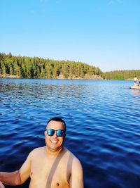 Portrait of shirtless man in lake against clear blue sky