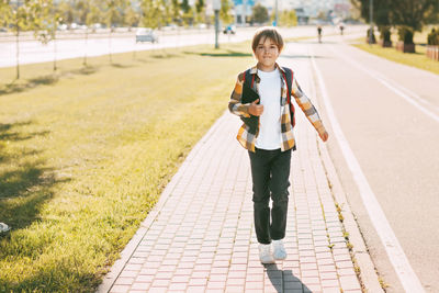 Full length portrait of smiling boy on footpath